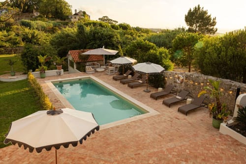 Sea'Ya Casa Pavão villa pool in Colares with loungers, umbrellas, and Mediterranean gardens at sunset