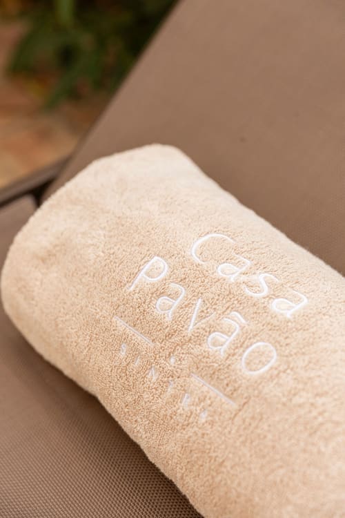 Beige rolled towel with Sea'Ya Villas embroidered in white text on tan surface