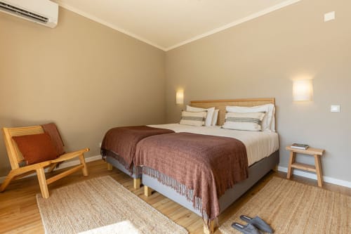 Spacious bedroom at Sea'Ya Casa Pavão villa in Colares with wooden bed frame, brown bedding, modern lighting, and minimalist