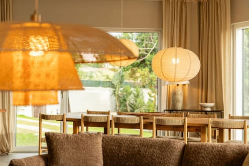 Dining area at Sea'Ya Casa Pavão villa with pendant lighting, wooden chairs, and garden views through large windows