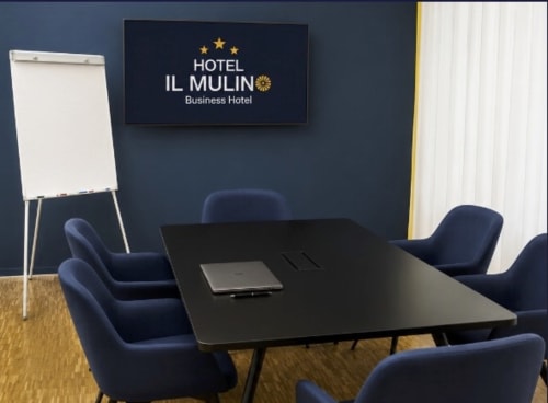 Sala riunioni dell'Hotel Il Mulino con sedie blu, tavolo nero e lavagna a Casalgrande, Italia