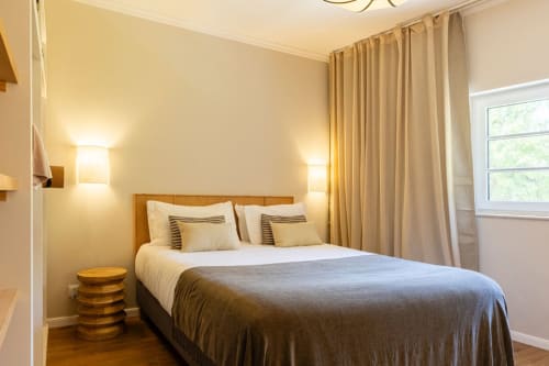 Cozy bedroom at Sea'Ya Casa Pavão villa in Colares with wooden bed, warm lighting, and garden view windows