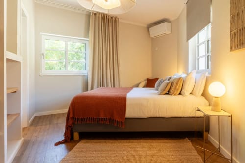 Bright bedroom at Sea'Ya Casa Pavão villa in Colares with king bed, terracotta throw, multiple pillows, natural light from