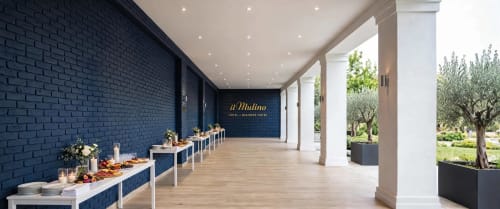 Moderna hall di hotel al Mulino con pareti in mattoni blu, elegante zona ristorazione, pavimenti in legno e colonne bianche