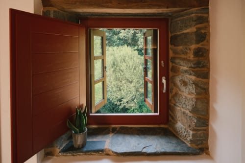 Entrada del apartamento Casa Grande de Covas en Taboada con puerta roja, planta en maceta y ventana abierta con vistas al verde