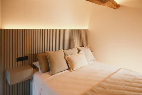 Dormitorio moderno en Casa Grande de Covas, Taboada con tonos neutros, cabecero de madera ondulada y ropa de cama contemporánea