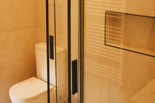 Baño moderno en apartamento Casa Grande de Covas con inodoro blanco, ducha con mampara de cristal y paredes con azulejos en tonos beige cálidos