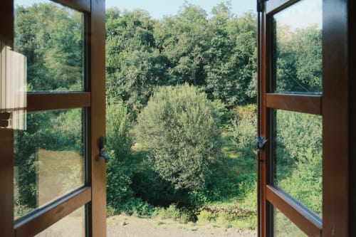 Puertas de madera abiertas enmarcando la vista del bosque verde y valle fluvial en Casa Grande de Covas, Taboada