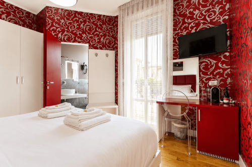 Camera moderna di B&B a Reggio Calabria con pareti rosse decorate, letto bianco, TV schermo piatto e bagno ensuite