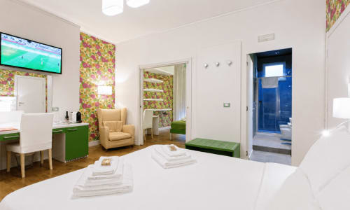 Suite moderna al B&B Pellicano con letto matrimoniale, zona living, dettagli verdi e bagno blu a Reggio Calabria