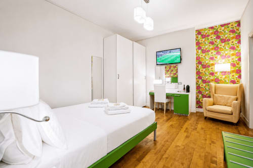 Suite moderna al B&B Pellicano a Reggio Calabria con letto bianco, accenti verdi, carta da parati colorata e separato