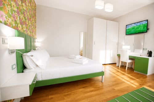 Suite moderna na B&B Pellicano Guest House em Reggio Calabria com estrutura de cama verde, roupa de cama branca, piso de madeira e TV ligada