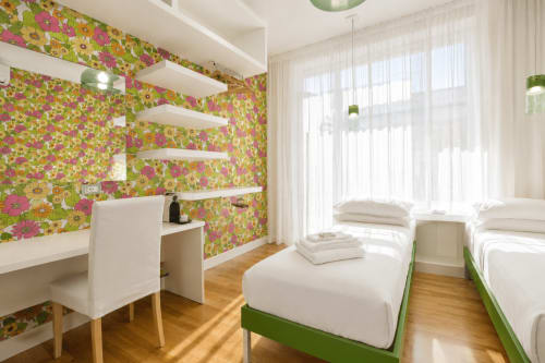 Camera da letto gemella luminosa presso la B&B Pellicano Guest House a Reggio Calabria con carta da parati floreale, scaffalature bianche e letto verde