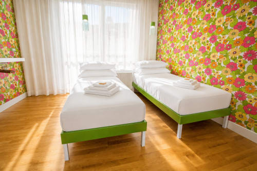 Luminosa camera doppia nella B&B Pellicano Guest House a Reggio Calabria con carta da parati floreale vivace, biancheria bianca e letto verde