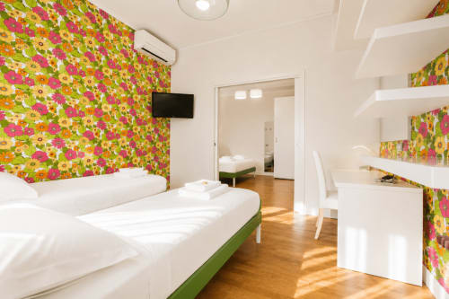 Suite luminosa alla B&B Pellicano con letti gemelli, carta da parati floreale colorata, pavimenti in legno e layout aperto a Reggio Calabria