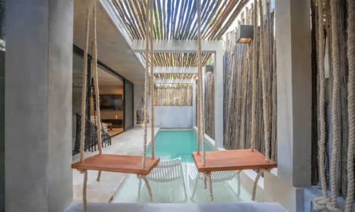 Zen Stays Tulum pool lounge with rope swings and turquoise water, modern design with white walls and woven screens