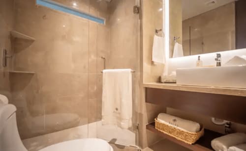 Baño moderno en Zen Stays Tulum con ducha de vidrio, lavabo blanco y tonos neutrales