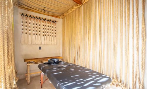 Minimalist bedroom at Zen Stays Tulum featuring wooden bed, macramé wall hanging, and natural light through sheer curtains