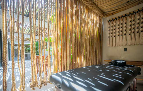 Habitación Zen Stays en Tulum con divisor de macramé, cama negra y detalles de techo de madera natural