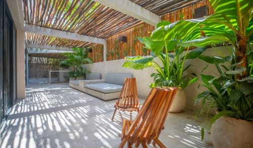Zen Stays Tulum terrace with wooden loungers, tropical plants, pergola shade, and modern seating area