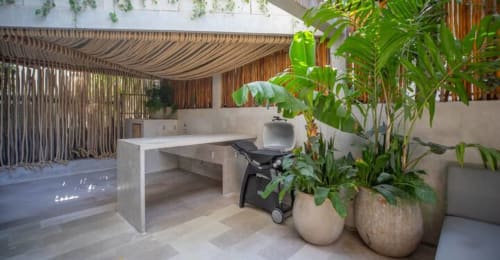Modern workspace at Zen Stays Tulum with white desk, tropical plants in ceramic pots, wooden pergola, and minimalist design