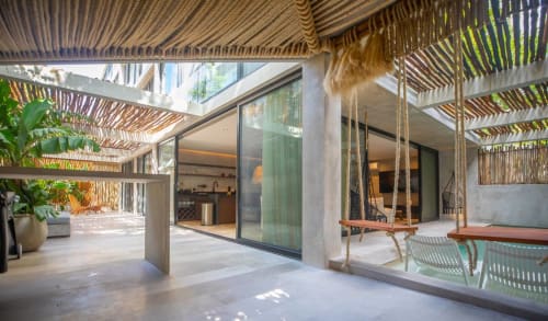 Modern patio at Zen Stays Tulum with wooden pergola, glass doors, hanging swing, and tropical plants
