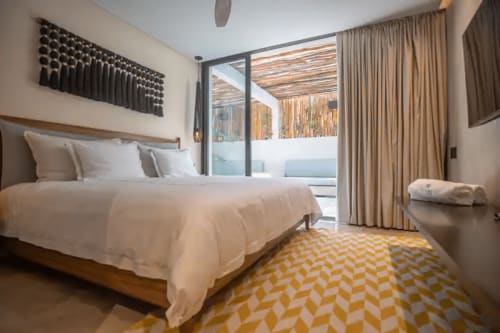 Moderno dormitorio en Zen Stays Tulum con cama blanca, terraza con vista al océano, alfombra geométrica y decoración minimalista.