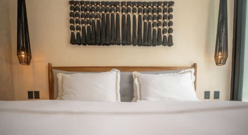 Zen Stays Tulum bedroom with wooden bed, white pillows, macramé wall art, and pendant lighting