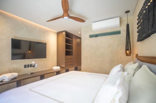 Habitación moderna en Zen Stays Tulum con ventilador de techo de madera, TV de pantalla plana, armario empotrado y ropa de cama blanca