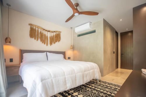Dormitorio moderno en Zen Stays Tulum con ropa de cama blanca, ventilador de techo de madera, lámparas colgantes y alfombra geométrica