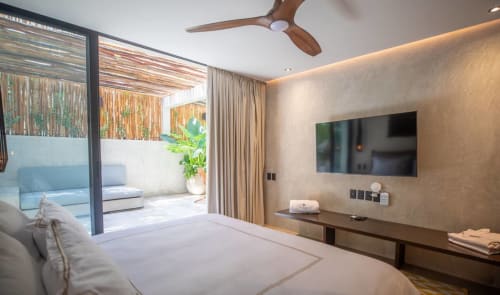 Modern bedroom at Zen Stays Tulum with king bed, flat-screen TV, wooden ceiling fan, and private balcony access
