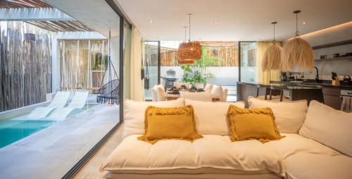 Lujosa suite con sábanas color crema, almohadas doradas, con vista a piscina y terraza en resort Zen Stays Tulum