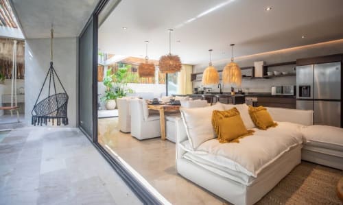 Habitación de lujo Zen Stays Tulum con vista al océano, mobiliario moderno, lámparas colgantes y espacio abierto