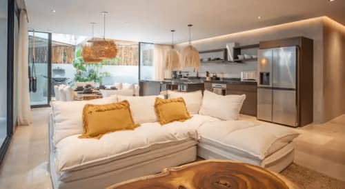 Modern open-plan living space at Zen Stays Tulum with cream sectional sofa, kitchen, and natural wood accents