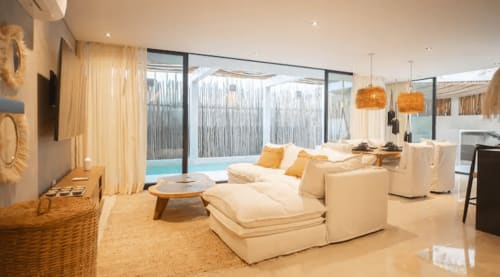 Zen Stays Tulum modern living room with cream furnishings, pool view, and warm lighting