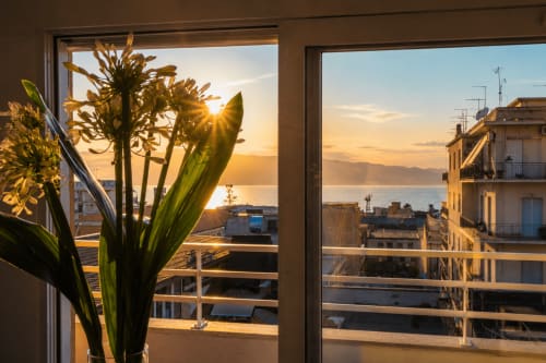 Vista del tramonto dalla terrazza di Pellicano Guest House a Reggio Calabria con fiori, vista sul mare e la Sicilia attraverso lo stretto
