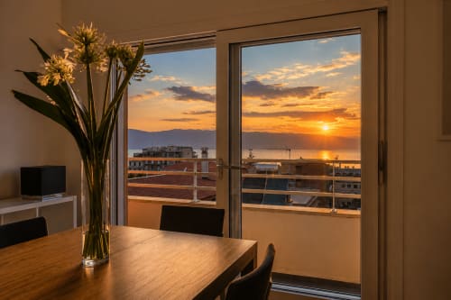 Vista tramonto dall'appartamento con vista mare della B&B Pellicano a Reggio Calabria, con fiori e televisione visibili nella stanza