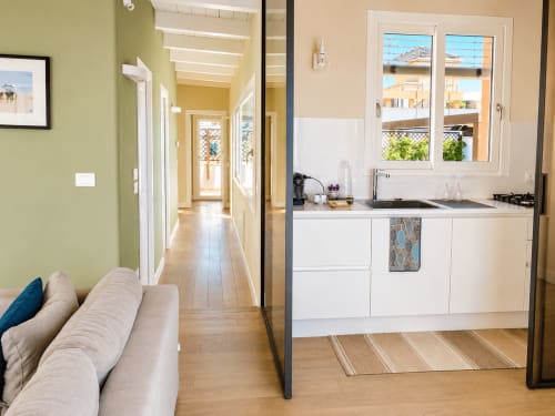 Cucina moderna e zona living in appartamento a Reggio Calabria con vista sul mare, arredamento bianco e finestre sulla Sicilia