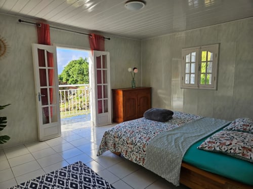 Chambre lumineuse à R'marine439 à Sainte-Rose avec portes-fenêtres donnant sur le jardin, lits doubles et ambiance tropicale