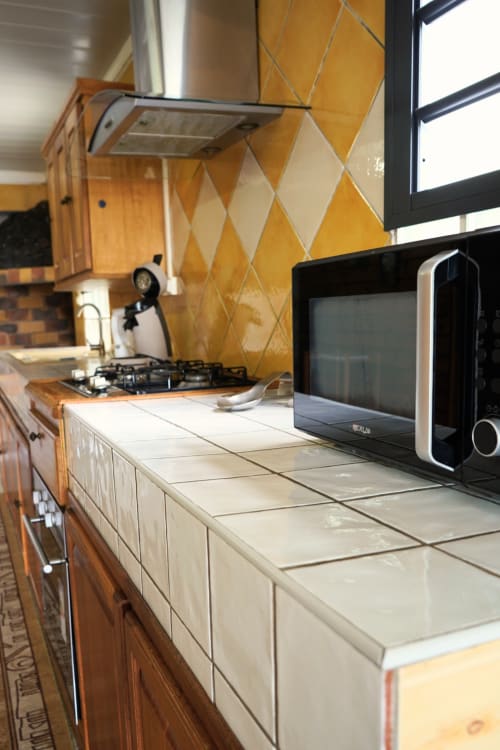 Cuisine moderne du bungalow R'marine439 avec dosseret en losanges jaunes, comptoirs crème, cuisinière à gaz et micro-ondes à Sainte