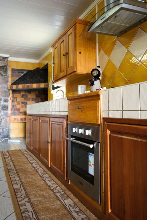 Cuisine moderne du Bungalow Le Cocotier à la Maison d'hôtes R'marine439 à Sainte Rose avec armoires en bois, four noir et carrelage jaune
