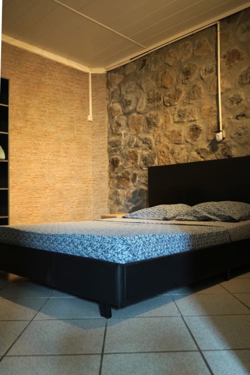 Chambre moderne du bungalow R'marine439 à Sainte-Rose avec lit queen-size, mur en pierre et climatisation