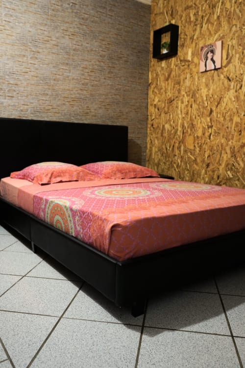 Lit aux motifs coralliens avec coussins roses dans le bungalow climatisé du R'marine439 BnB, Sainte-Rose Réunion