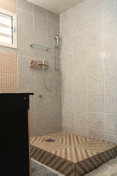 Douche moderne avec petits carreaux de mosaïque et sol en pierre rayée à R'marine439 BnB à Sainte-Rose