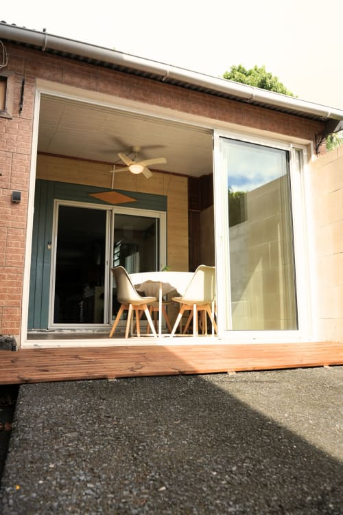 Terrasse de bungalow R'marine439 à Sainte Rose avec terrasse en bois, chaises modernes, ventilateur de plafond et portes vitrées