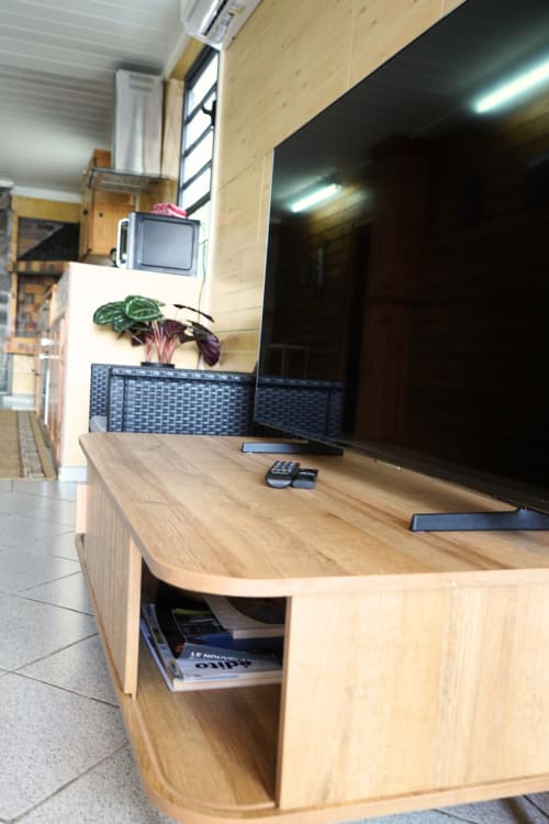 Meuble TV moderne en bois avec écran plat, plante en pot et rangements au bungalow R'marine439 à Sainte-Rose