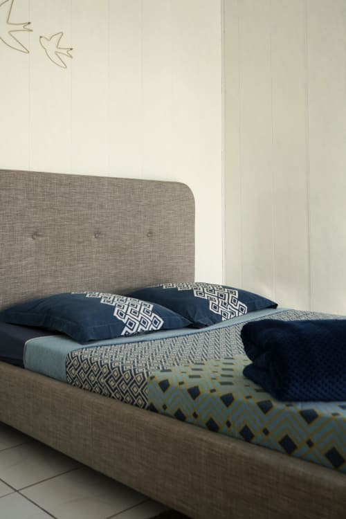 Lit haut de gamme avec tête de lit grise, oreillers à motifs bleu marine et linge de lit géométrique au gîte R'marine439 à Sainte-Rose