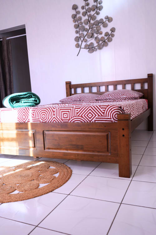 Lit en bois avec literie géométrique rouge dans le cottage Caz' mangoustan du R'marine439 BnB, Sainte-Rose, sol carrelé