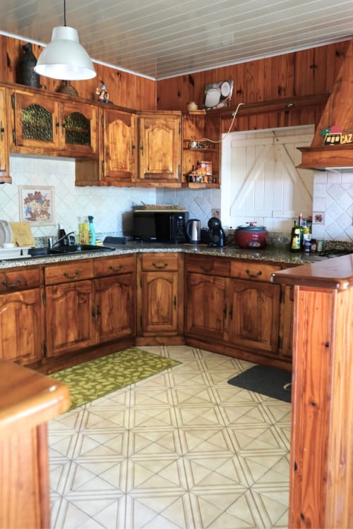 Cuisine rustique en bois du gîte Caz' mangoustan à R'marine439, Sainte-Rose, avec comptoirs en granit et carrelage blanc
