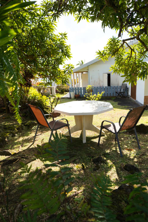 Terrasse de jardin ombragée avec table ronde et chaises orange au gîte R'marine439 à Sainte-Rose